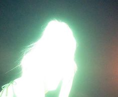 a woman holding a cell phone up to her ear with the light shining on her