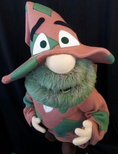 a close up of a stuffed animal wearing a green and brown hat with big eyes