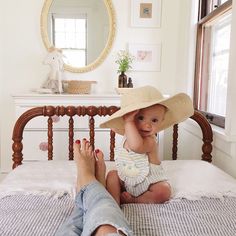 a baby sitting on top of a bed with a hat on it's head