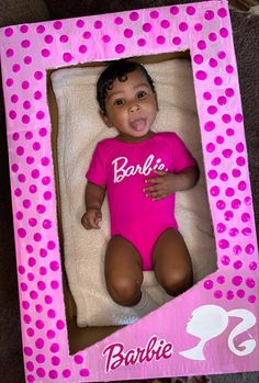 a baby doll in a pink box with polka dots on the bottom and an inscription that says barbie