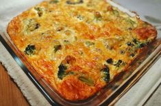 a square casserole dish with broccoli and cheese on the top is sitting on a napkin