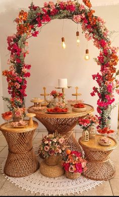 a table with flowers and candles on it in front of a white wall that is decorated with wicker