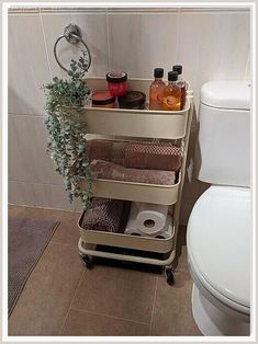 a bathroom with a toilet next to a shelf filled with towels and other items on it