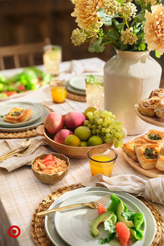 a table topped with plates and bowls filled with food next to flowers in a vase