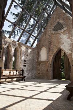 the inside of an old brick building with a wooden bench in front of it and large windows