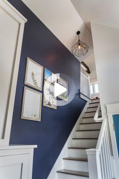 a staircase with pictures on the wall next to it and a light fixture hanging from the ceiling