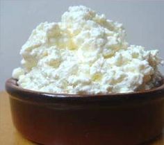 a brown bowl filled with whipped cream on top of a wooden table