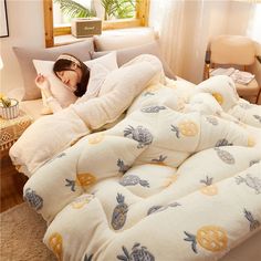 a woman laying on top of a bed covered in blankets and pineapple print pillows