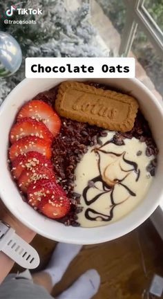 a bowl filled with chocolate and strawberries next to a cookie on top of it