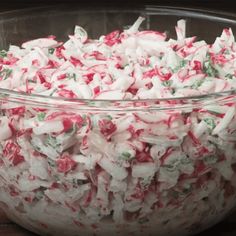 a large bowl filled with candy canes on top of a wooden table