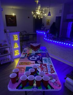 a long table with cups on it in the middle of a room filled with lights