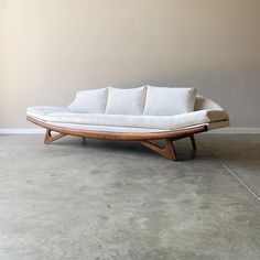 a white couch sitting on top of a cement floor next to a brown and white wall