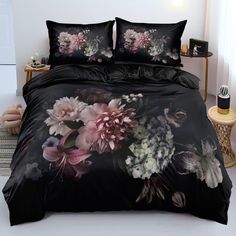 a bed with black comforter covers and flowers on it