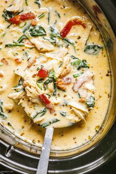 a spoon in a bowl filled with soup and spinach on top of the table