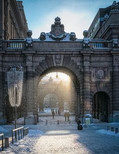 the sun shines through an archway in a snowy city