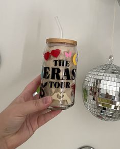 a hand holding a glass jar filled with confetti next to a disco ball