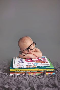 a baby wearing glasses is laying on top of several children's books in front of a gray background