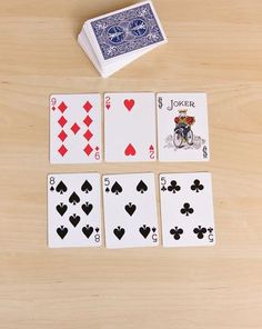 four playing cards and two dice on a wooden table with one card in the middle