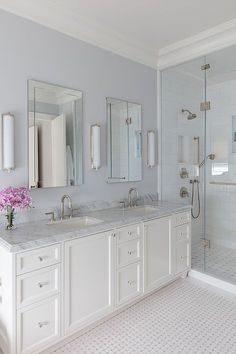 a large bathroom with two sinks and three mirrors on the wall, along with a walk in shower