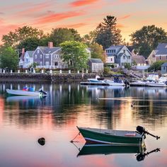 a boat is sitting on the water in front of some houses and boats at sunset