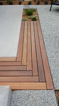 a wooden deck in the middle of a graveled area