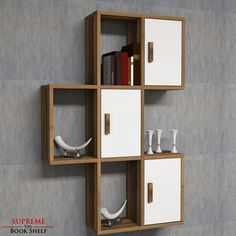 a book shelf with two white drawers and some books on it's sides, in front of a gray wall