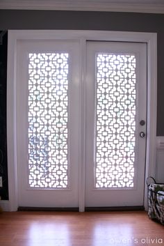 a white double door with decorative screen on the glass and wood flooring in front of it