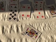 playing cards are laid out on the sand in preparation to be put into their respective game