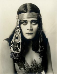 an old photo of a woman with long hair wearing headdress and jewelry on her face