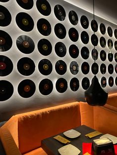 a room with orange couches and record records on the wall behind it, as well as a black table