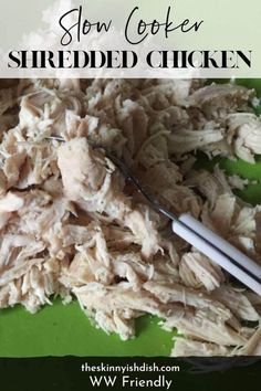 shredded chicken on a green plate with a fork in it and the words slow cooker shredded chicken