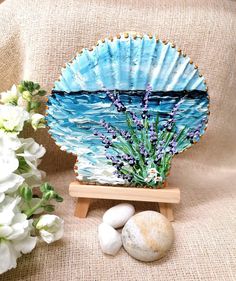 a blue plate sitting on top of a wooden stand next to white flowers and rocks