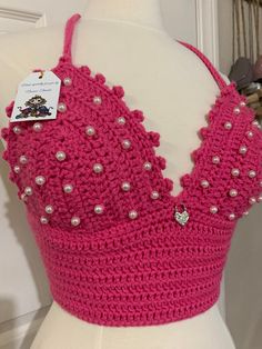 a crocheted top with pearls on the back and straps is displayed in front of a mannequin