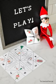 an elf is sitting next to a game board with letters and numbers on it that says let's play