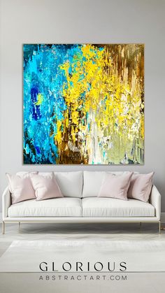 an abstract painting in blue, yellow and white on a wall above a couch with pillows