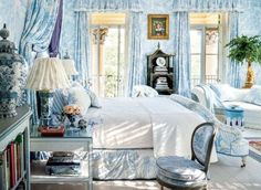 the bedroom is decorated in blue and white with an ornate bed, chair, desk, and window