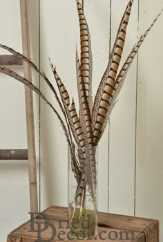 a vase filled with feathers sitting on top of a wooden table