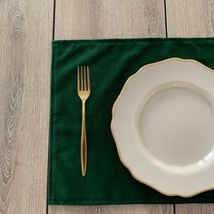 a green place mat with a white plate and gold fork