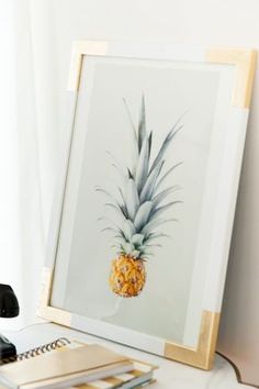 a pineapple sitting on top of a white table next to a pen and paper