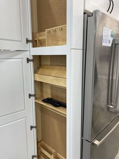 a stainless steel refrigerator freezer sitting inside of a kitchen next to white cupboards