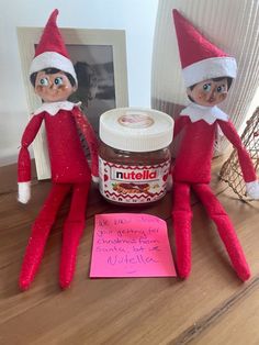 two elfs are sitting next to a jar of peanut butter and a note that says nutella