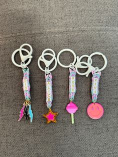 six key chains with different designs on them sitting on a gray surface next to each other