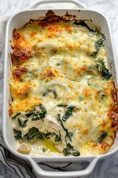 a casserole dish with spinach and cheese in it on a marble surface