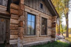 an old log cabin with wood siding and windows