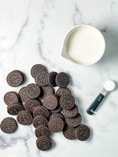 oreo cookies next to a bowl of milk and a spoon on a marble surface