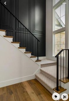 the stairs in this house are painted black and have wood treading on them, along with white walls