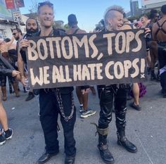 two men holding a sign that says bottoms tops we all hate cops