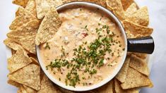 a white bowl filled with dip surrounded by tortilla chips