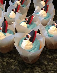 cupcakes with blue frosting and red headbands on them sitting on a counter