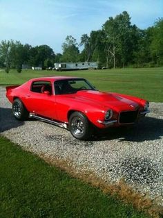 a red car parked on top of a gravel road